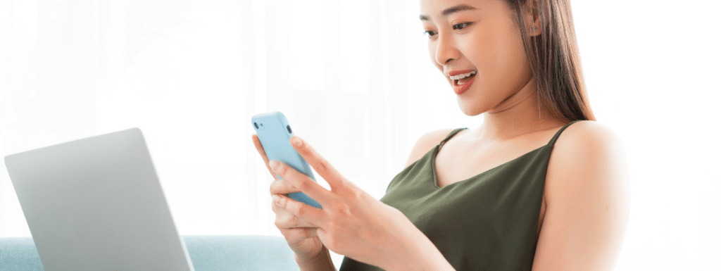 White person with long dark hair holding and looking an a phone.