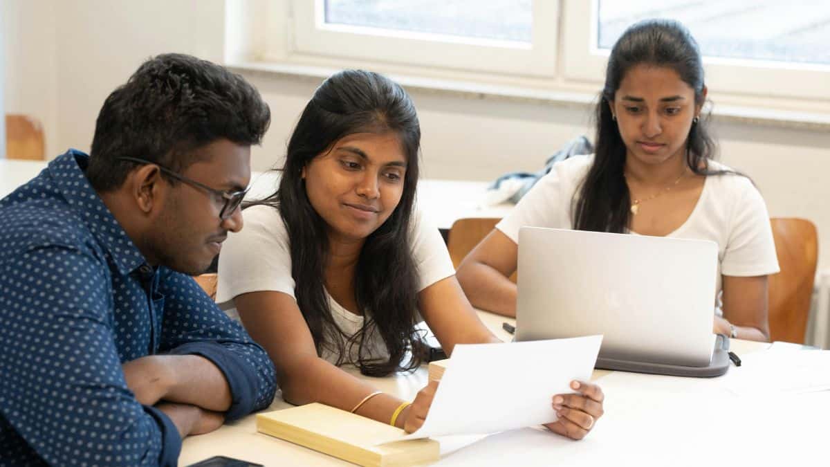 Three people at a table looking at papers and a laptop
