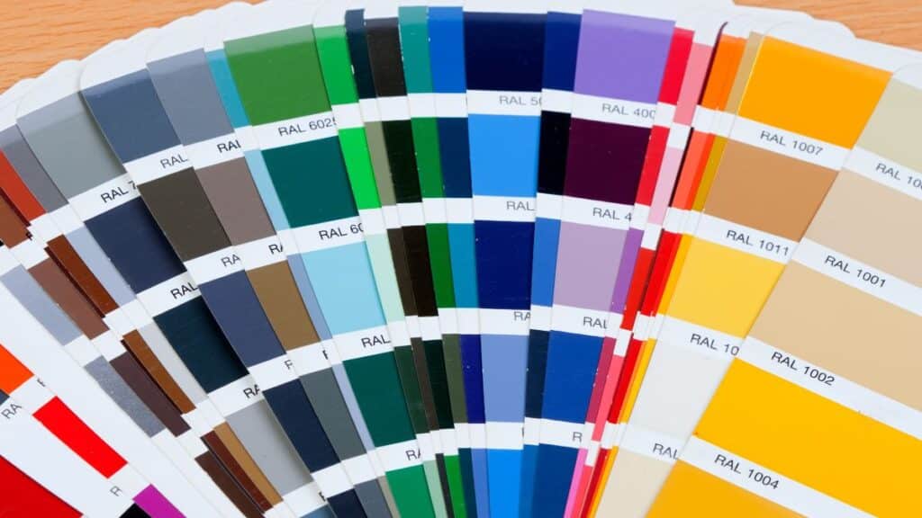 A fanned-out set of colour reference cards arranged in a rainbow gradient displayed on a wooden surface.