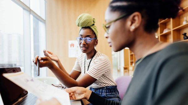 Two people looking at papers and computer